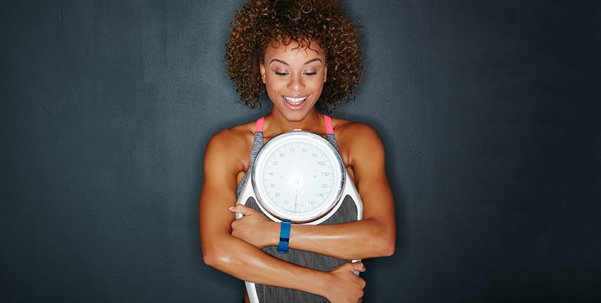 a happy woman hugging a weight scale