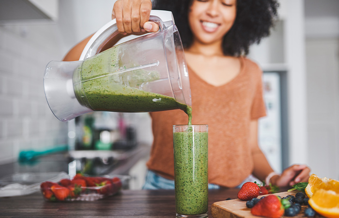 woman pouring a green smoothie 